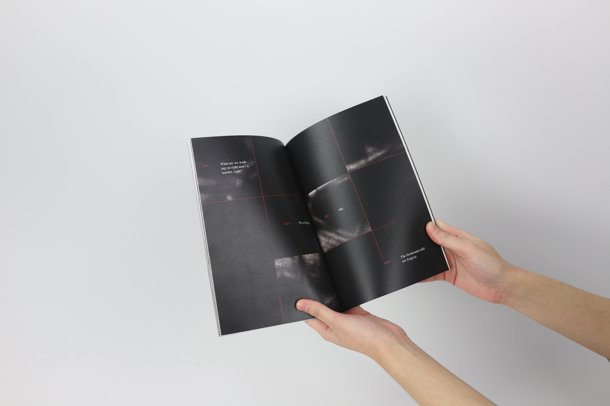 Hands holding open a book to a dark spread