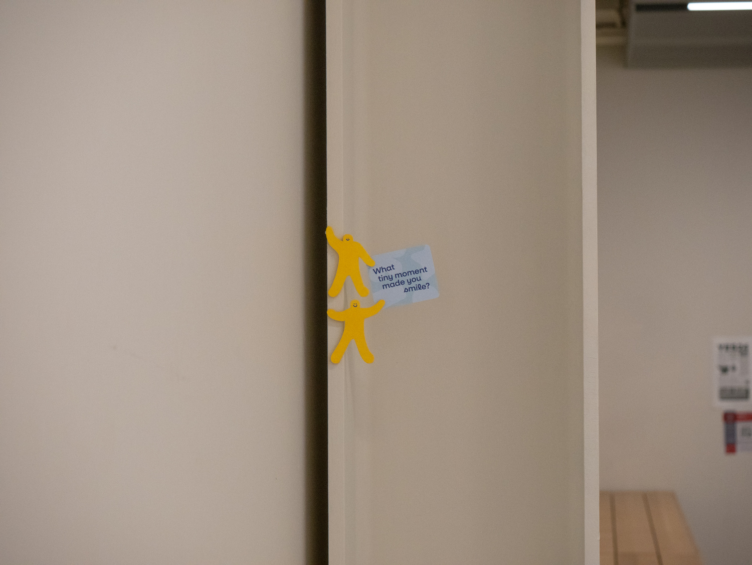 Small cutouts of human figures hanging on the wall and holding a cheerful sign